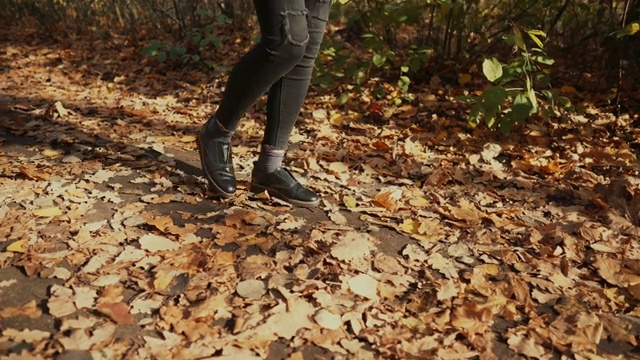 少女独自走在秋天的森林在白天，近距离的脚视频素材