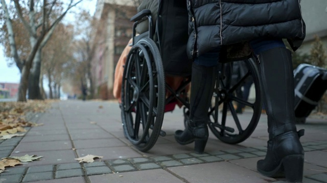 一个女人推着另一个坐轮椅的女人穿过城市视频素材