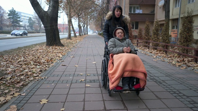 社工用轮椅推着一位老年妇女视频素材