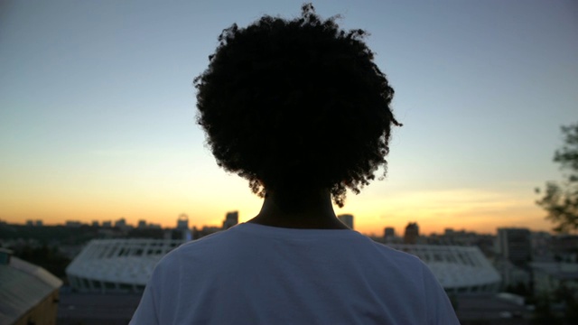 美国黑人卷发妇女在屋顶上享受日落，沉思，后视镜视频素材