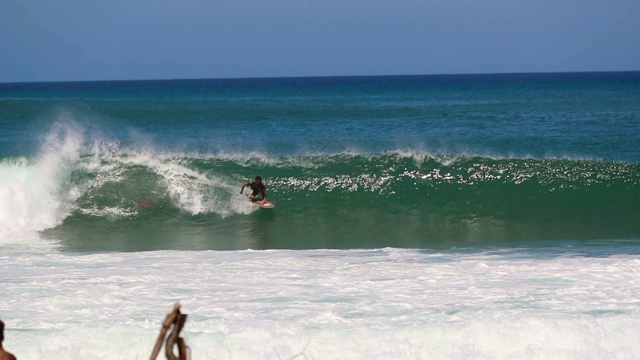 观众在海滩上看冲浪者在慢动作的波浪在夏威夷视频下载