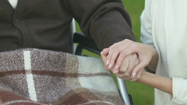 妇女在轮椅上牵着病人的手，志愿者计划，慈善理念视频素材