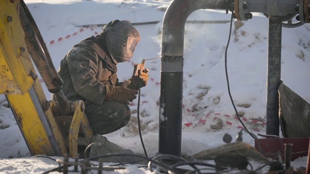 工人在街上进行管子焊接。在冬季，温度较低的情况下，很难安装管道钢丝视频下载