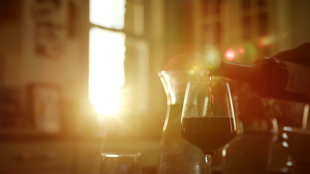 一名男子将红酒倒进餐桌上的杯子里视频素材