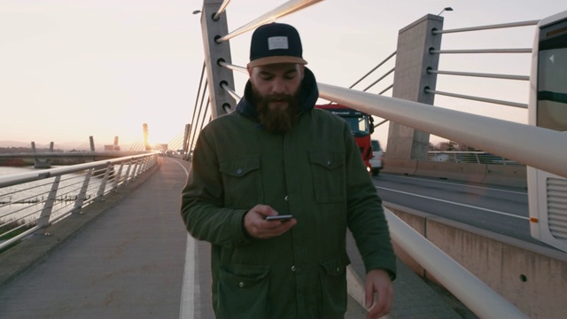 MS Man用智能手机在桥上行走视频素材