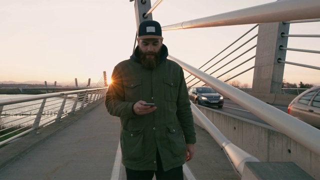 在桥上行走和使用智能手机的男子视频素材