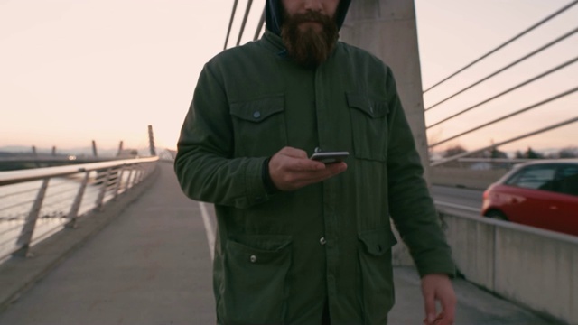 MS Man带着智能手机，在桥上走路发短信视频素材