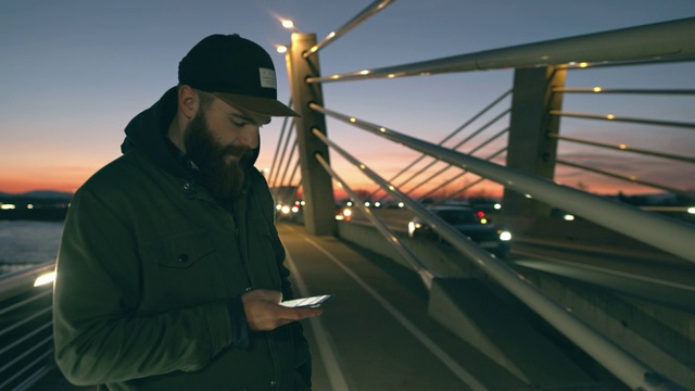 MS Man黄昏时在桥上用智能手机视频素材