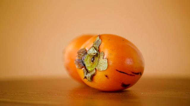 成熟的甜柿子配上橙色的背景视频下载