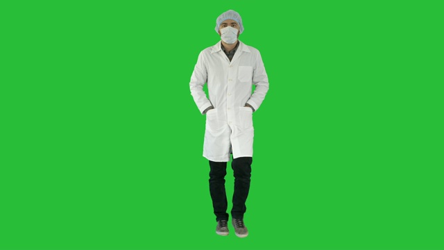 行走的年轻男医生戴着外科口罩在绿色屏幕上，色度钥匙视频素材