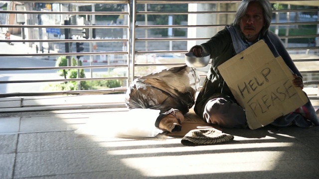 一个无家可归的人坐在地上向人们乞讨视频下载
