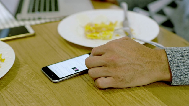 cuman在吃饭时使用智能手机和笔记本电脑视频下载