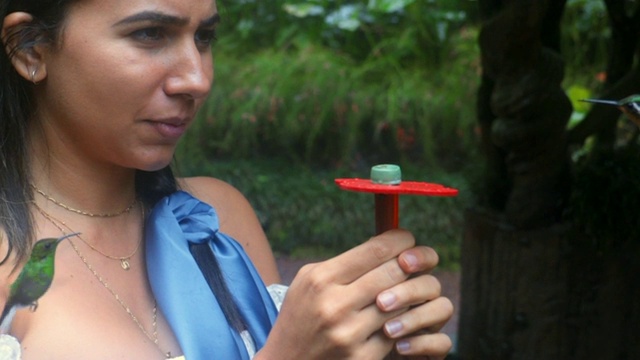 慢镜头:一个年轻女子拿着蜂鸟饮水器的特写视频素材