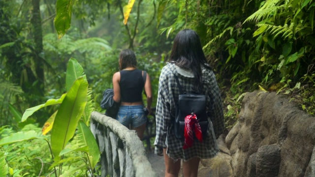 慢镜头:两个年轻女人在热带雨林的徒步小径上行走视频素材