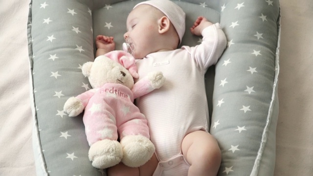 穿粉红色衣服的可爱小女孩睡在茧床里视频素材
