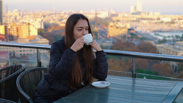 在巴塞罗那，一位女士在户外咖啡馆喝咖啡，那里有着令人惊叹的景色视频素材