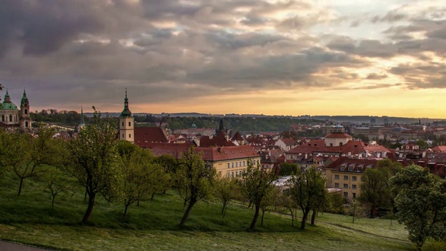 布拉格老城的屋顶，圣尼古拉斯教堂，树木和建筑物从公园与幼树，时间的推移，白天春天阴天捷克共和国视频下载