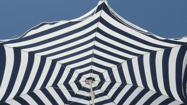 蓝色和白色沙滩遮阳伞催眠效果4K 2160p 30fps超高清镜头-条纹伞太阳防护织物在风中移动3840X2160超高清视频视频下载