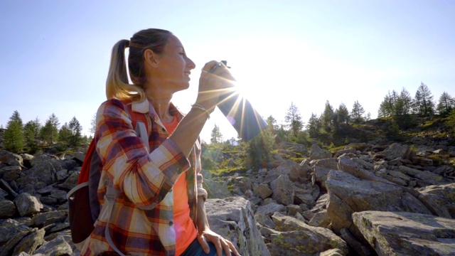 徒步旅行的女人用水瓶在山路上喝水。在瑞士阿尔卑斯山徒步旅行的女人有一个休息和喝从瓶子视频素材