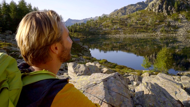 徒步男从水瓶中在山间小道上饮水。一名在瑞士徒步旅行的男子停下来喝水休息视频素材
