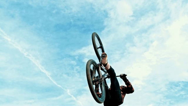 在蓝天白云的映衬下，年轻男子跳跃和后空翻BMX自行车视频素材