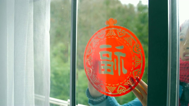 妇女把中国传统剪纸贴在窗户上视频素材