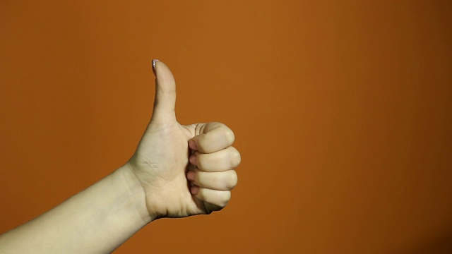 手势的概念是双手竖起大拇指，作为庆祝和祝贺获胜者孤立在橙色背景上视频下载