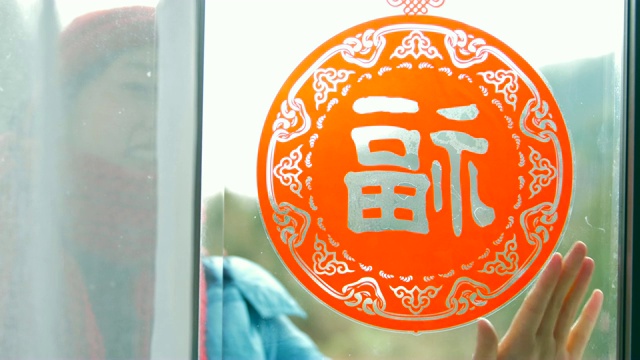 妇女把中国传统剪纸贴在窗户上视频素材