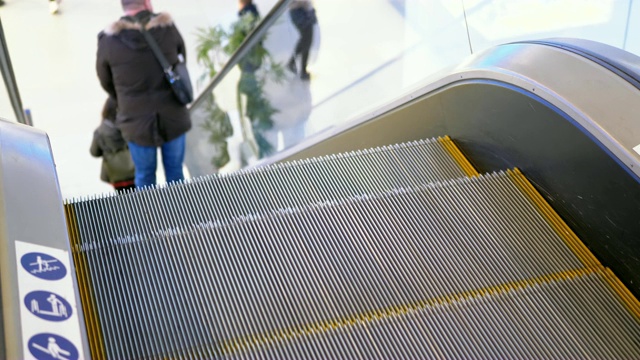 购物中心里人们在自动扶梯上移动的腿。慢动作视频素材