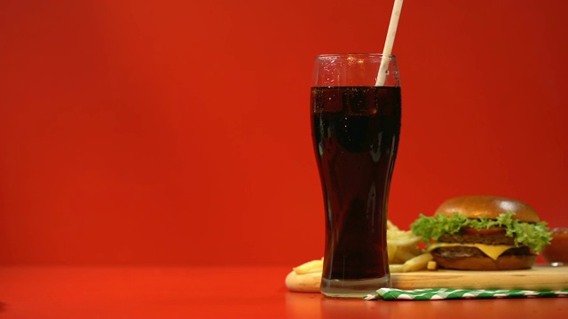 软饮料和汉堡，对垃圾食品上瘾，红色背景作为警告视频素材