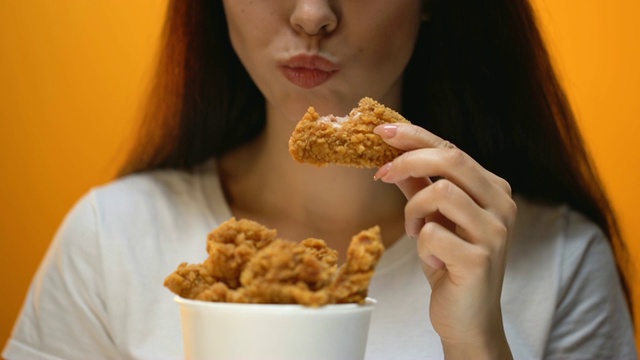 女孩吃鸡翅，高热量食物和健康风险，胆固醇视频下载