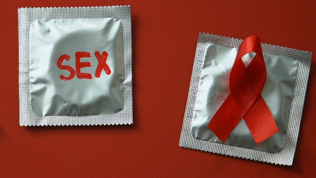 避孕套以红色的性安全字为背景，警惕艾滋病的性病概念视频下载