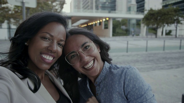 微笑的多民族妇女在城市里打手势和视频通话视频下载