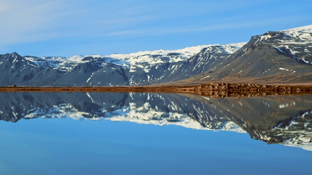 一辆行驶在道路上的汽车穿过宁静的山湖，冰岛视频素材