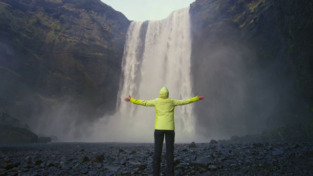 冰岛斯科加佛斯瀑布，一位女士伸出双臂站在那里视频素材