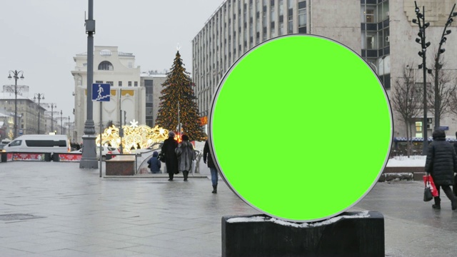 一个带有绿色屏幕的大型圆形广告牌，安装在街道上，作为新年的装饰。视频素材