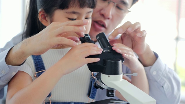 亚洲小孩和老师在学校实验室用显微镜观察。小女孩用显微镜学习科学课。教育的主题视频素材