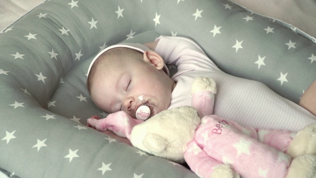 一个在一个假人的粉红色帽子里睡觉的婴儿的脸的特写视频素材