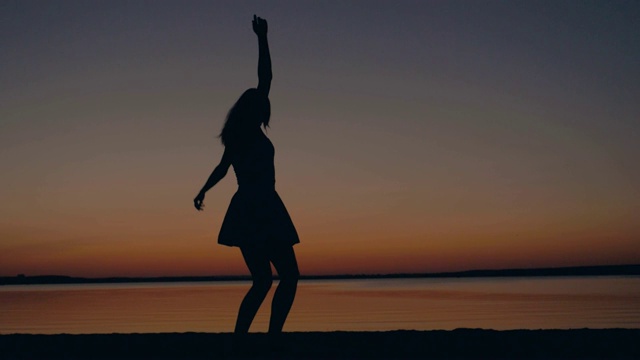 快乐的女人跑向日落到海滩举起她的手臂和旋转视频素材