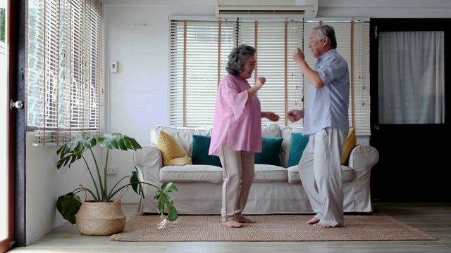 这对浪漫的老年情侣在一起跳舞的同时也显示出他们的内心依然年轻。高中情侣在家跳舞。家庭在泰国。视频素材