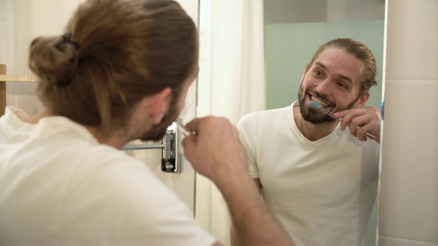 男人在浴室里刷牙和照镜子视频素材