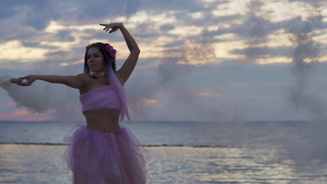 可爱的女孩与闪闪发光的妆在粉红色的裙子在河岸上跳舞。一个性感的女人的舞蹈与一个美妙的发型和鲜花。缓慢的运动。视频素材