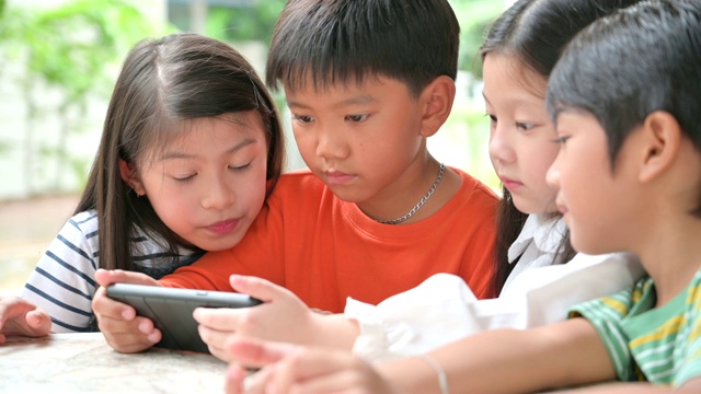 一大群年轻的男孩和女孩共享平板电脑和智能手机技术视频素材