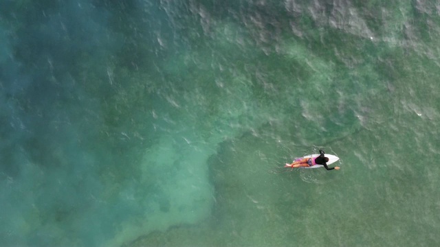 中景，一个成熟的女人在冲浪板上划水视频下载