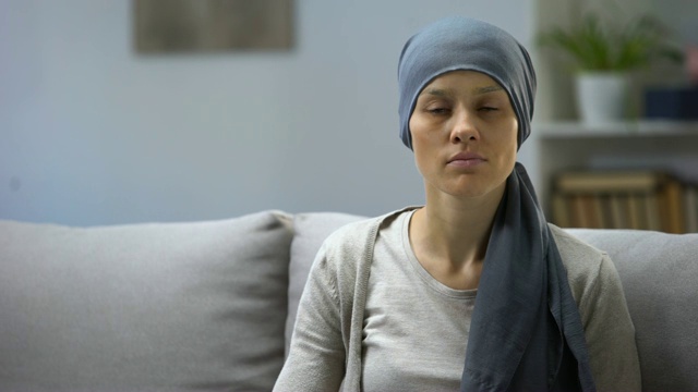 化疗后的妇女坐在家里看着摄像机，背景视频素材
