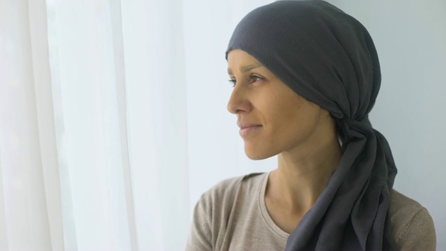 幸福的女人戴着头巾在窗口看，癌症治疗后恢复视频素材