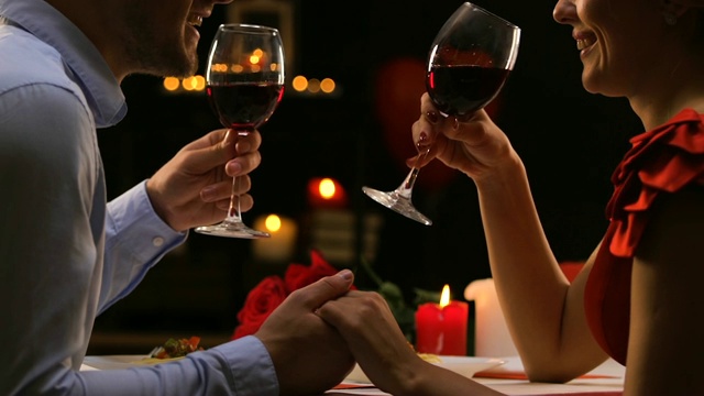 热恋中的情侣聊天喝红酒，惬意地庆祝情人节视频下载