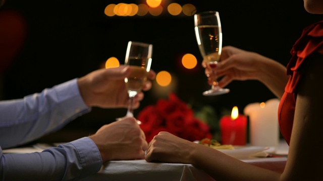 夫妻喝着香槟，男人温柔地抚摸着女人的手，浪漫的夜晚视频下载