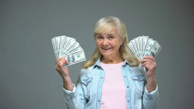 微笑的高级妇女展示美元钞票，快速贷款服务，银行视频素材