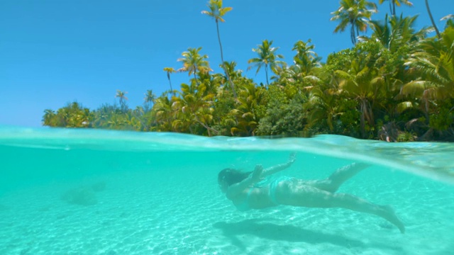 慢镜头:快乐的女游客在天堂岛海滩潜水。视频下载